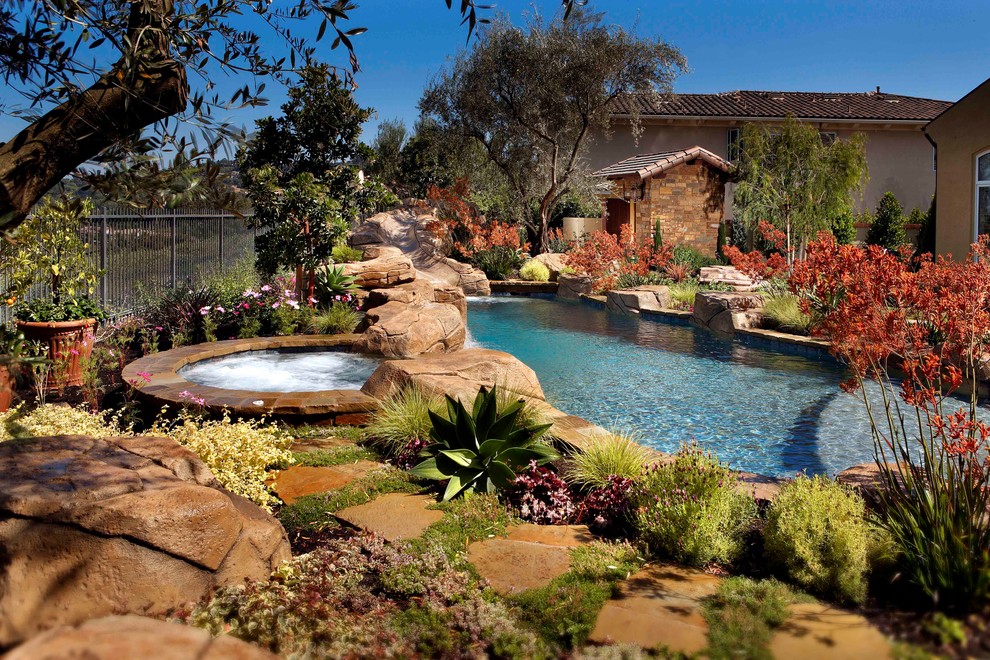 Modelo de piscina con tobogán natural clásica grande a medida en patio trasero con adoquines de piedra natural