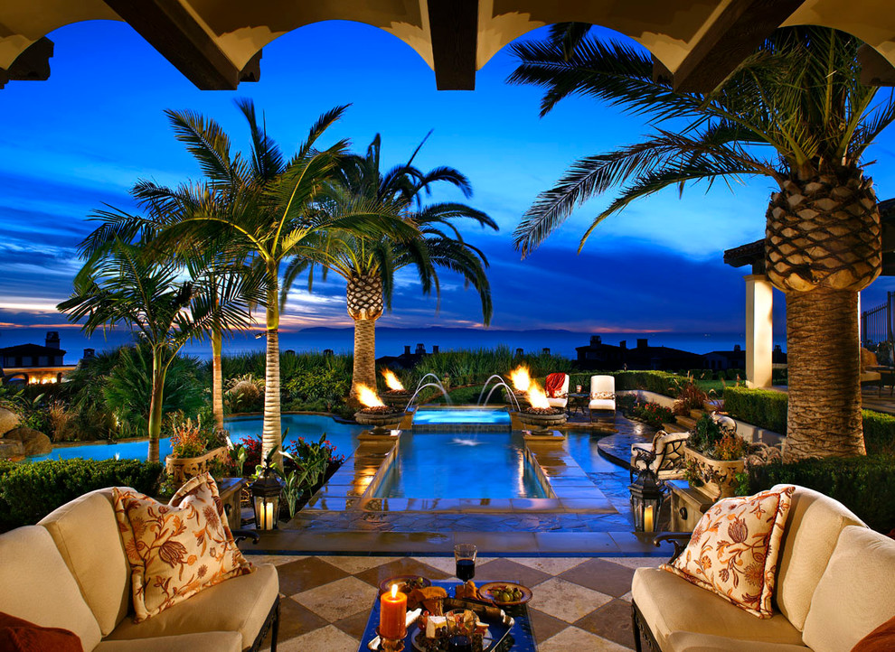Foto di una grande piscina tropicale personalizzata dietro casa con fontane e piastrelle