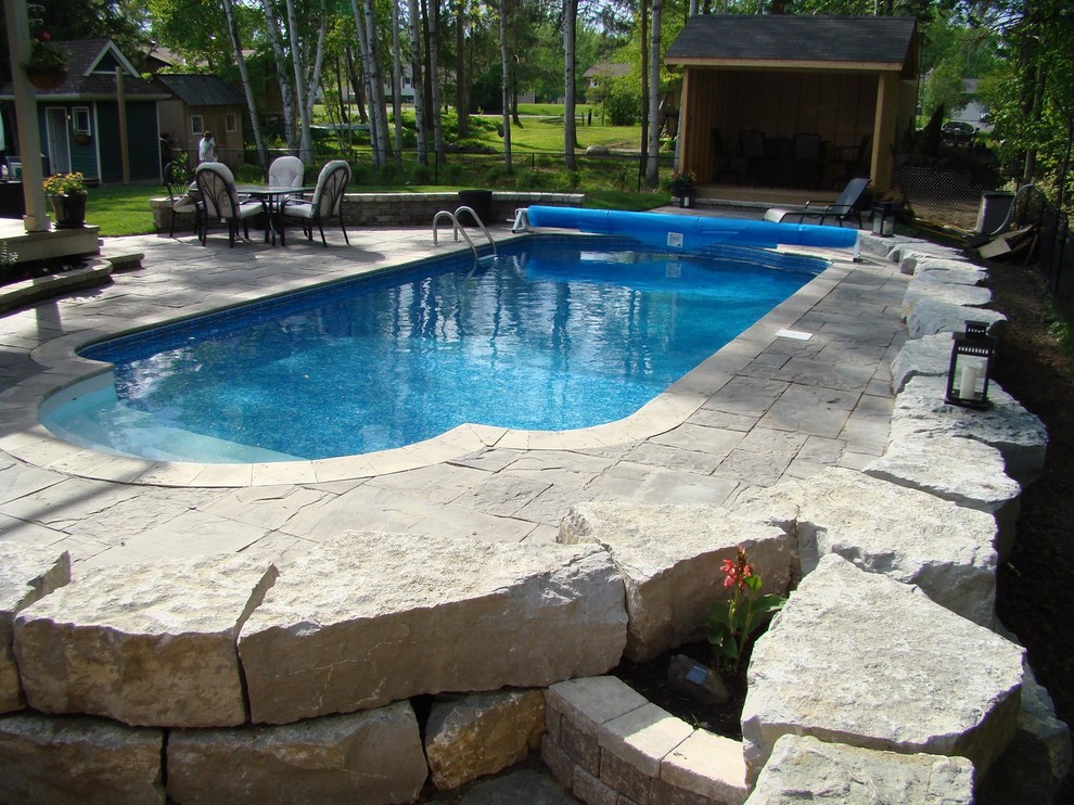 Ejemplo de piscina alargada tradicional de tamaño medio a medida en patio trasero con adoquines de piedra natural