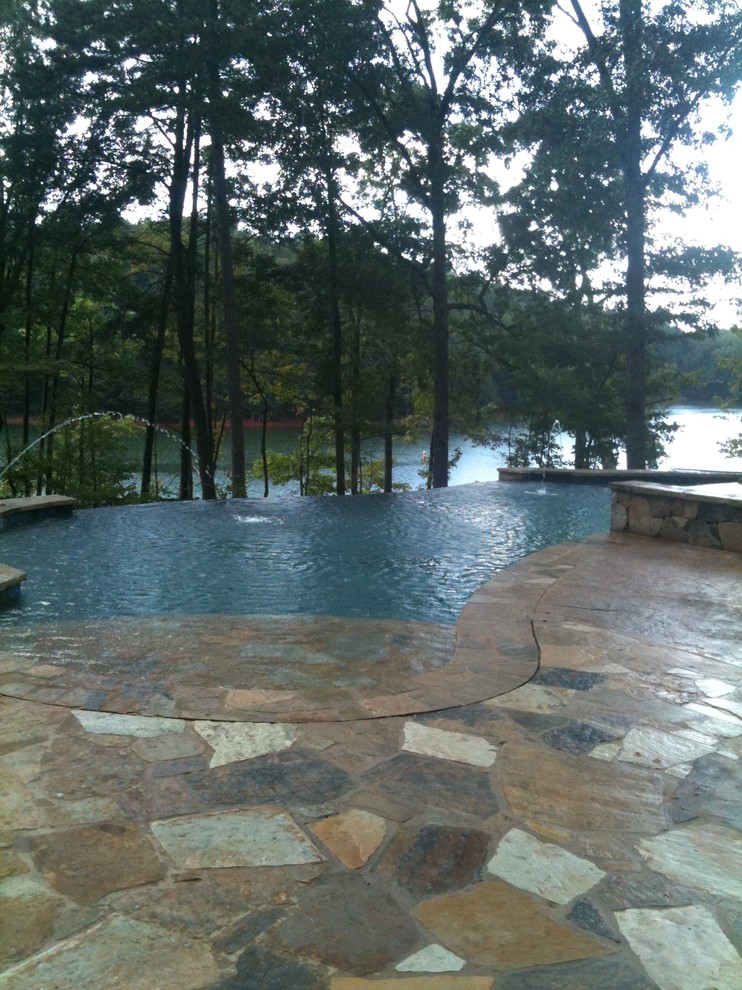 Large mountain style backyard stone and custom-shaped infinity hot tub photo in Atlanta