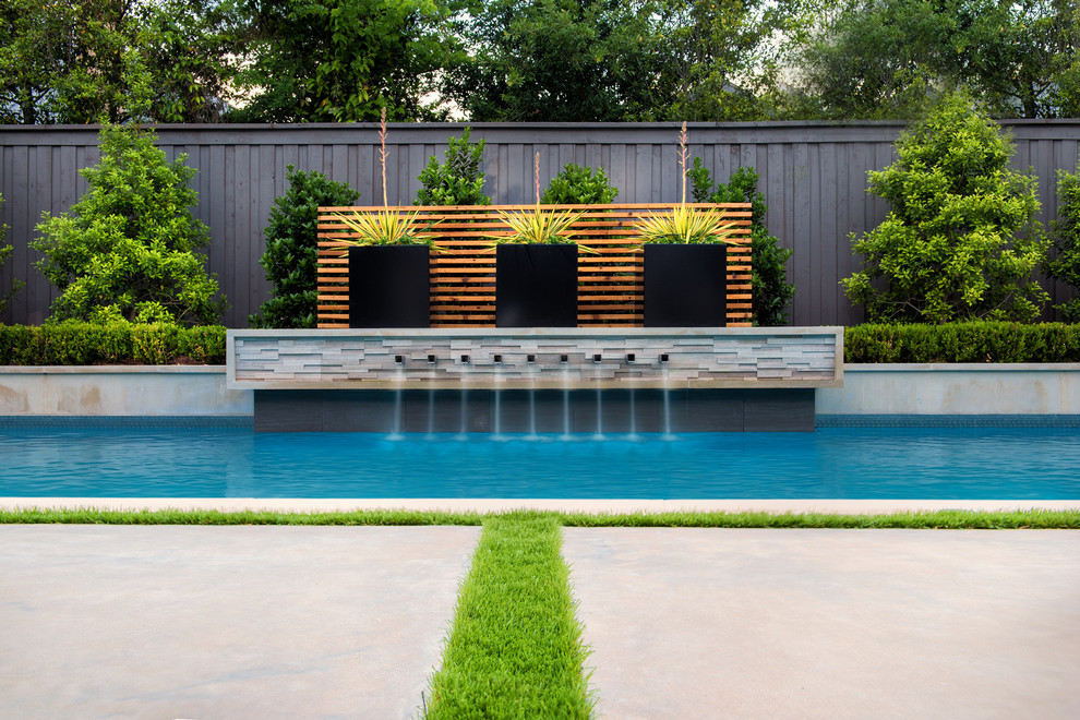 Immagine di una piscina minimalista rettangolare di medie dimensioni e dietro casa con una vasca idromassaggio e lastre di cemento