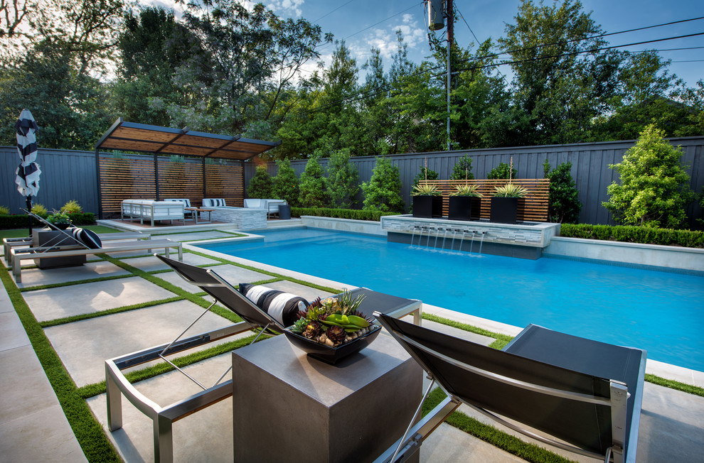Medium sized modern back rectangular hot tub in Dallas with concrete slabs.