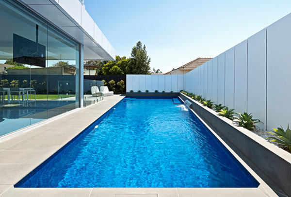Foto de piscina con fuente alargada minimalista grande a medida en patio lateral con adoquines de piedra natural