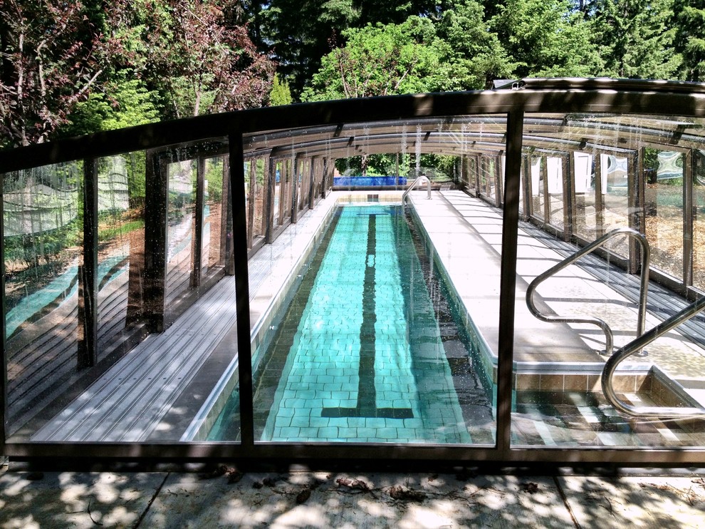 Modelo de piscina alargada ecléctica de tamaño medio rectangular en patio trasero con suelo de baldosas