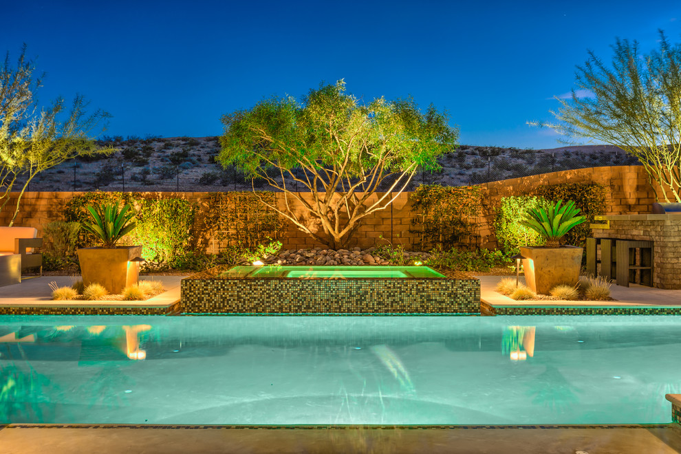 Esempio di una grande piscina monocorsia tropicale rettangolare dietro casa con una vasca idromassaggio e pavimentazioni in pietra naturale