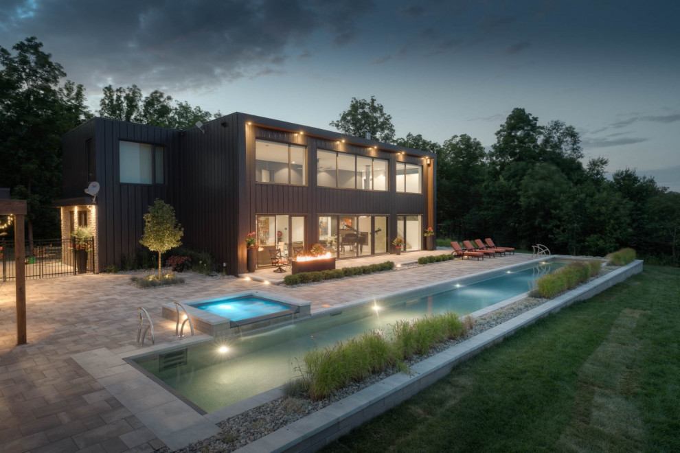 Idee per un'ampia piscina monocorsia moderna rettangolare dietro casa con una vasca idromassaggio e pavimentazioni in pietra naturale