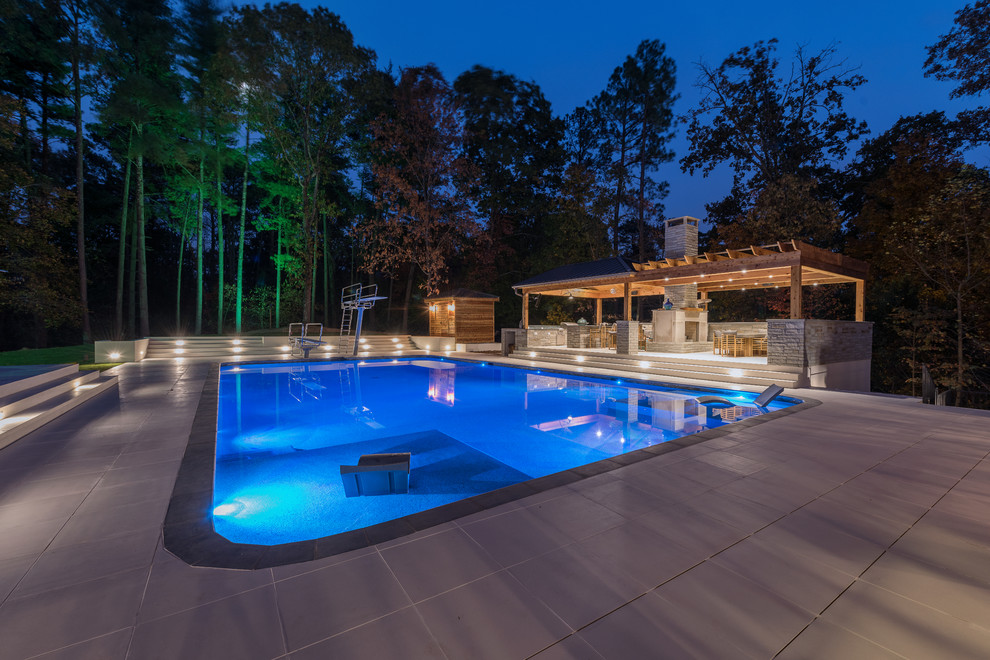 Ejemplo de casa de la piscina y piscina actual grande rectangular con suelo de baldosas