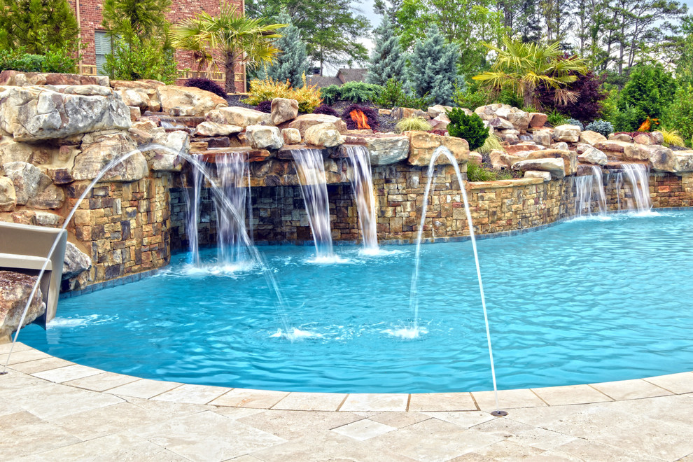 Immagine di una grande piscina naturale personalizzata dietro casa con un acquascivolo e pedane