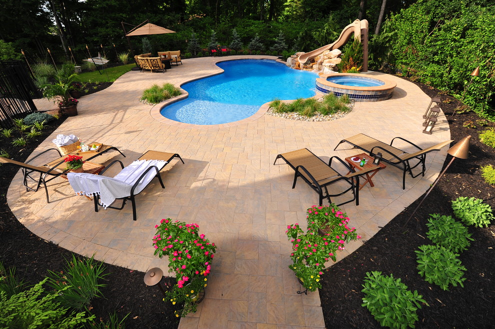 Ejemplo de piscinas y jacuzzis clásicos renovados grandes a medida en patio trasero con adoquines de hormigón