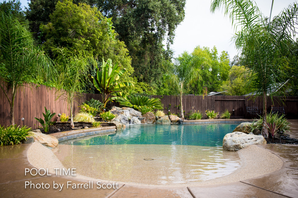 Imagen de piscina con fuente clásica grande a medida en patio trasero con suelo de hormigón estampado