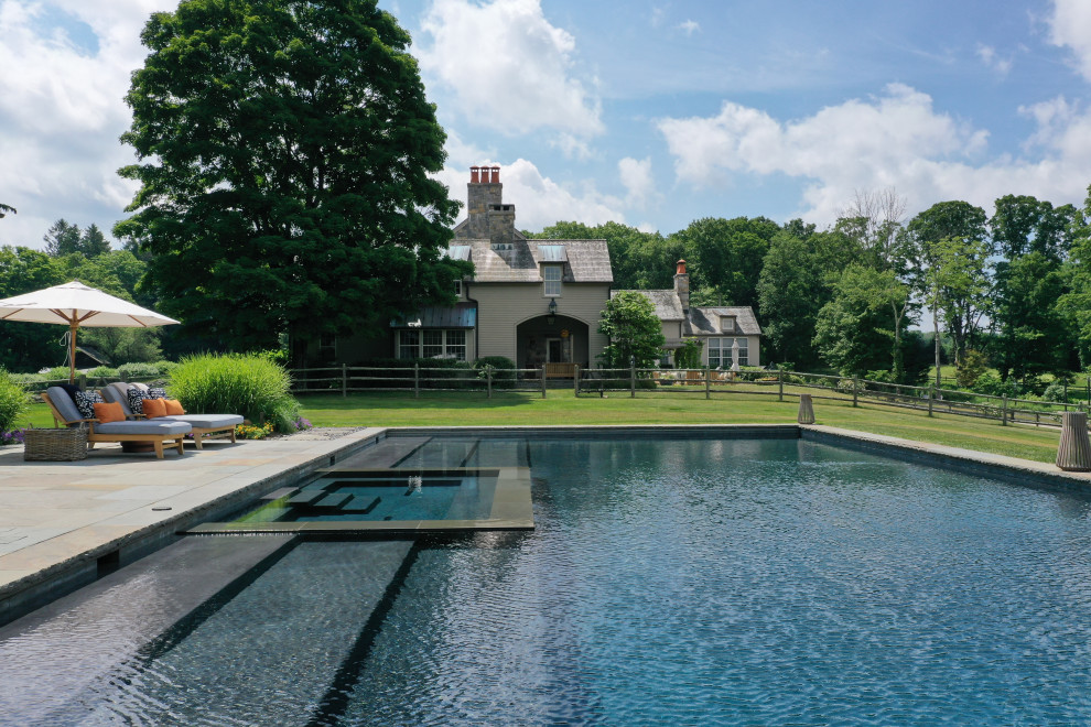 Ejemplo de casa de la piscina y piscina tradicional grande rectangular en patio trasero con adoquines de piedra natural