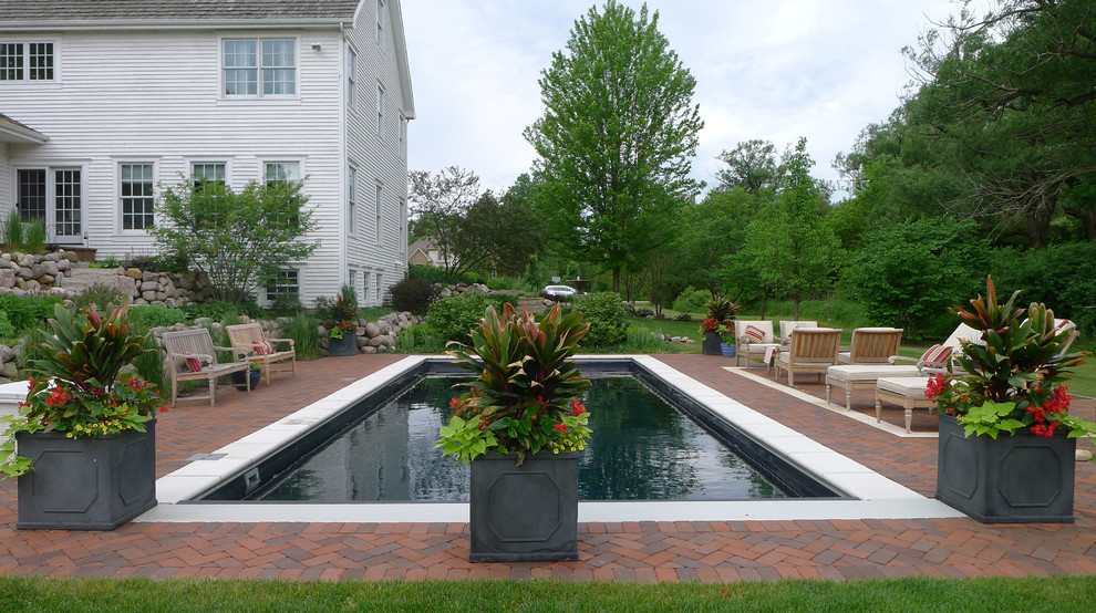 Imagen de piscina campestre de tamaño medio rectangular en patio trasero con adoquines de ladrillo