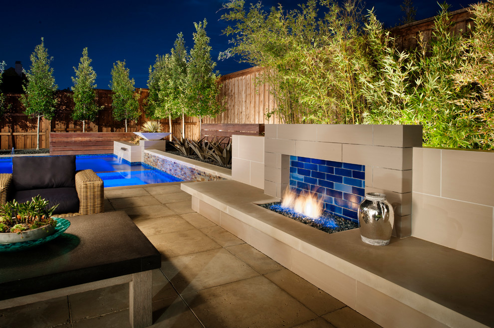 Cette image montre une piscine arrière minimaliste en L de taille moyenne avec un point d'eau et une terrasse en bois.