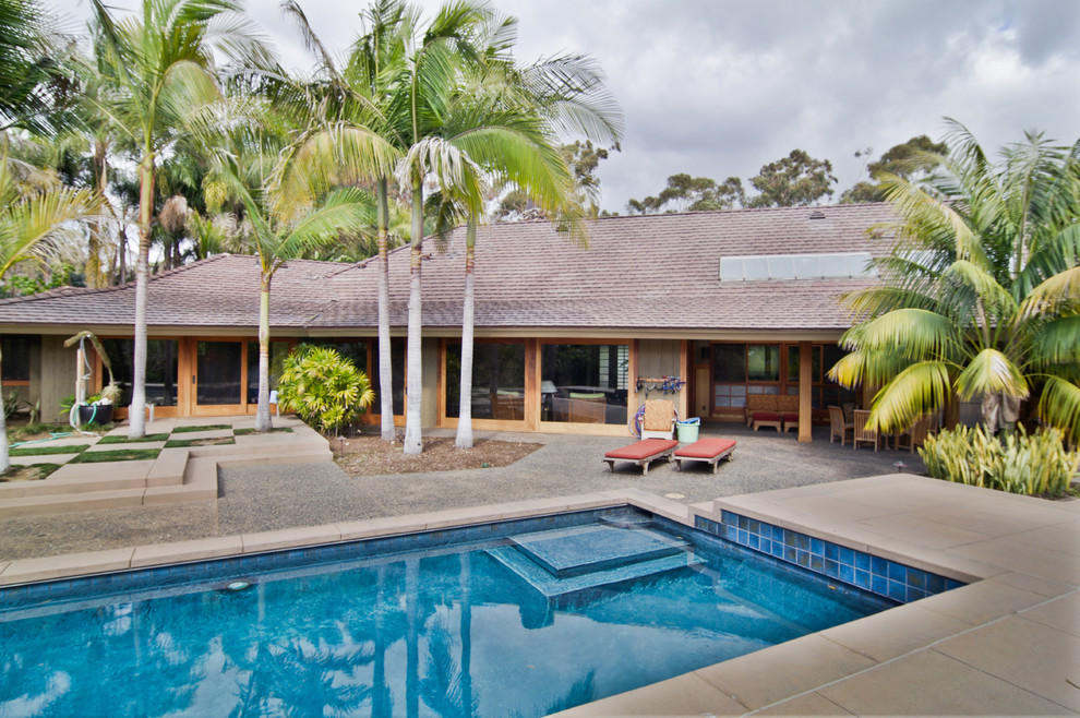 Diseño de piscina alargada exótica grande rectangular en patio trasero con losas de hormigón