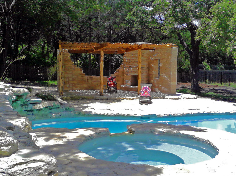 Esempio di una grande piscina naturale stile americano a "C" dietro casa con pavimentazioni in pietra naturale e una vasca idromassaggio