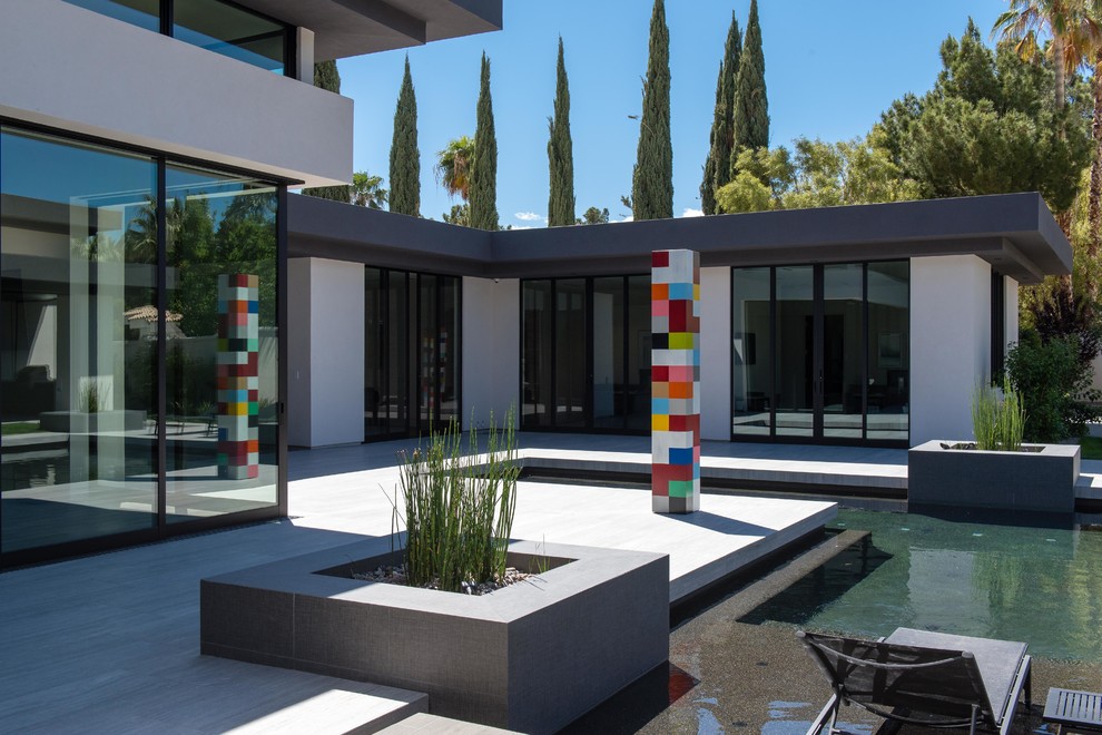 Foto di una grande piscina monocorsia minimalista personalizzata dietro casa con piastrelle e una vasca idromassaggio