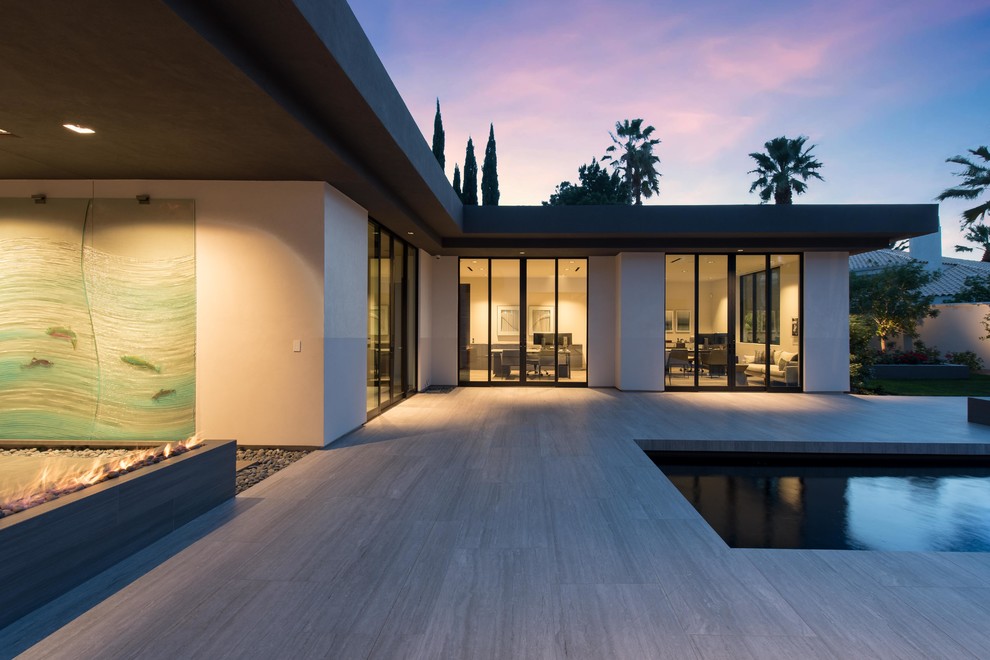Immagine di una grande piscina monocorsia minimalista personalizzata dietro casa con piastrelle e una vasca idromassaggio