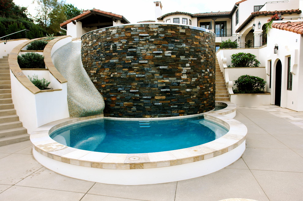 This is an example of a small mediterranean round swimming pool in San Diego with stamped concrete and a water slide.