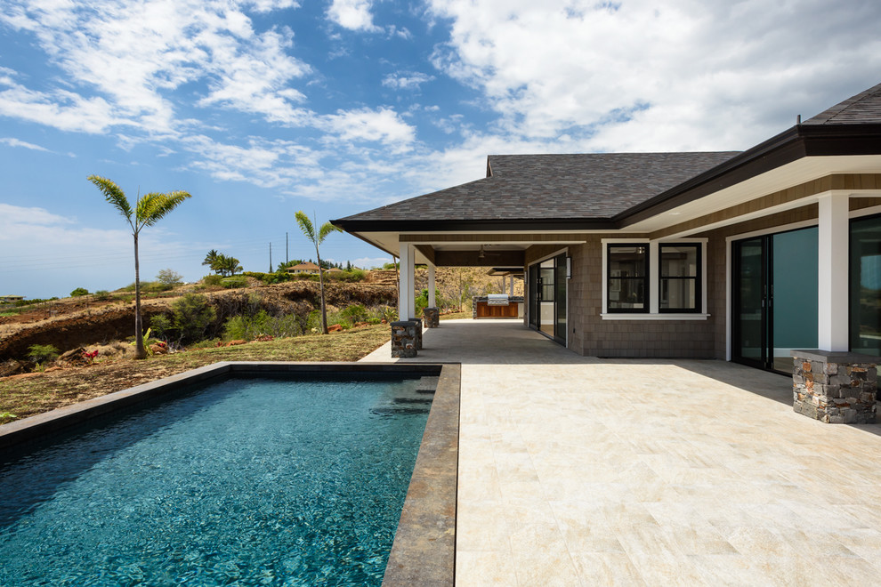 Immagine di una grande piscina costiera rettangolare dietro casa con piastrelle