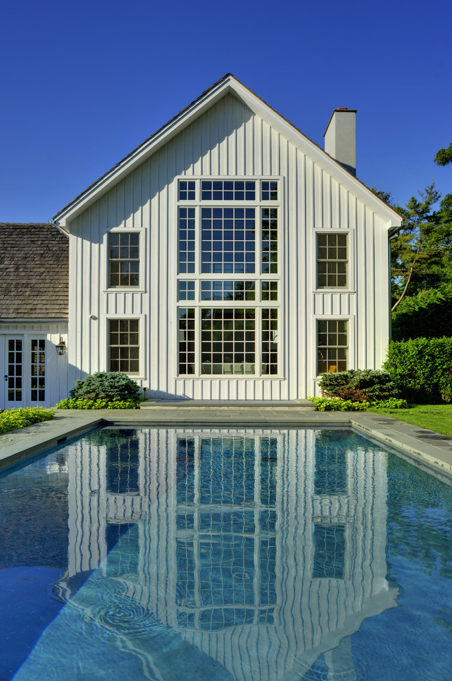 Ejemplo de piscina alargada clásica grande rectangular en patio trasero con adoquines de hormigón