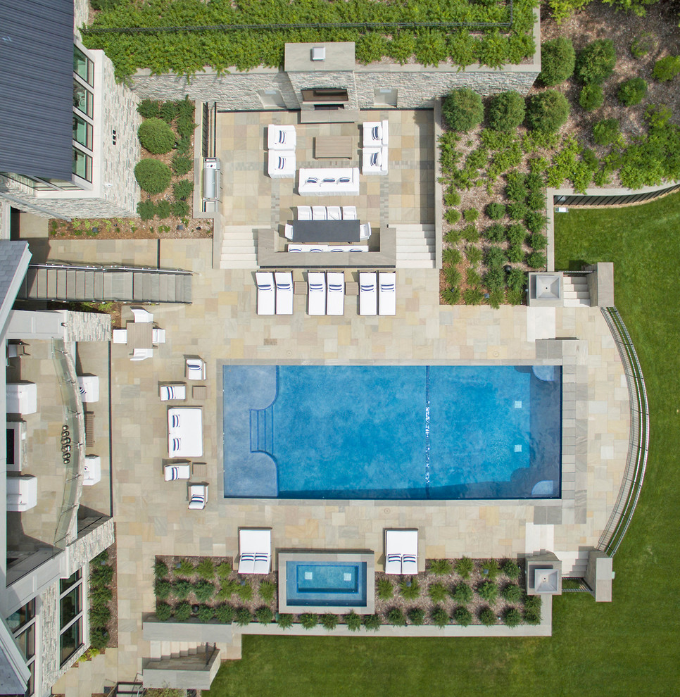 Modelo de piscina contemporánea extra grande rectangular en patio trasero con adoquines de piedra natural