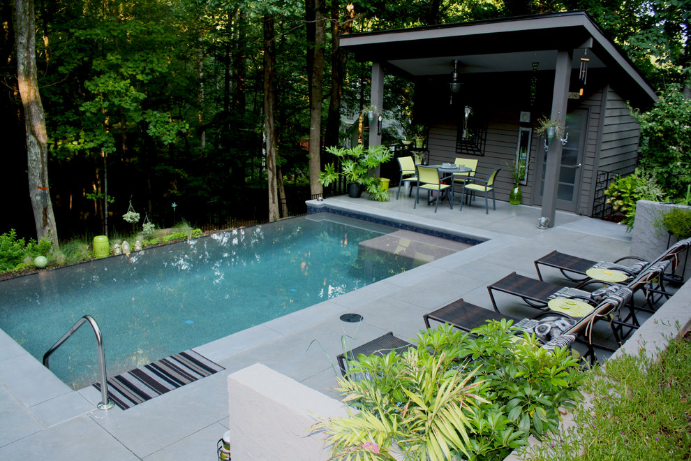 Modelo de casa de la piscina y piscina infinita contemporánea de tamaño medio rectangular en patio trasero con adoquines de hormigón