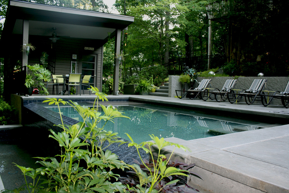 Esempio di una piscina a sfioro infinito contemporanea rettangolare di medie dimensioni e dietro casa con una dépendance a bordo piscina e pavimentazioni in cemento