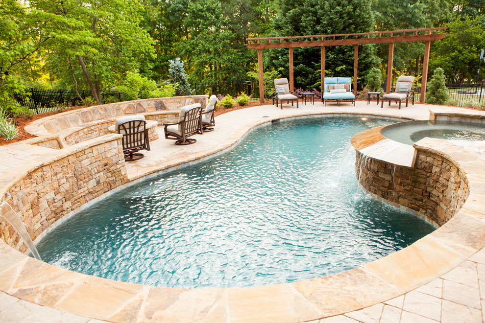 Idee per una grande piscina monocorsia tradizionale a "C" dietro casa con una vasca idromassaggio e pavimentazioni in pietra naturale