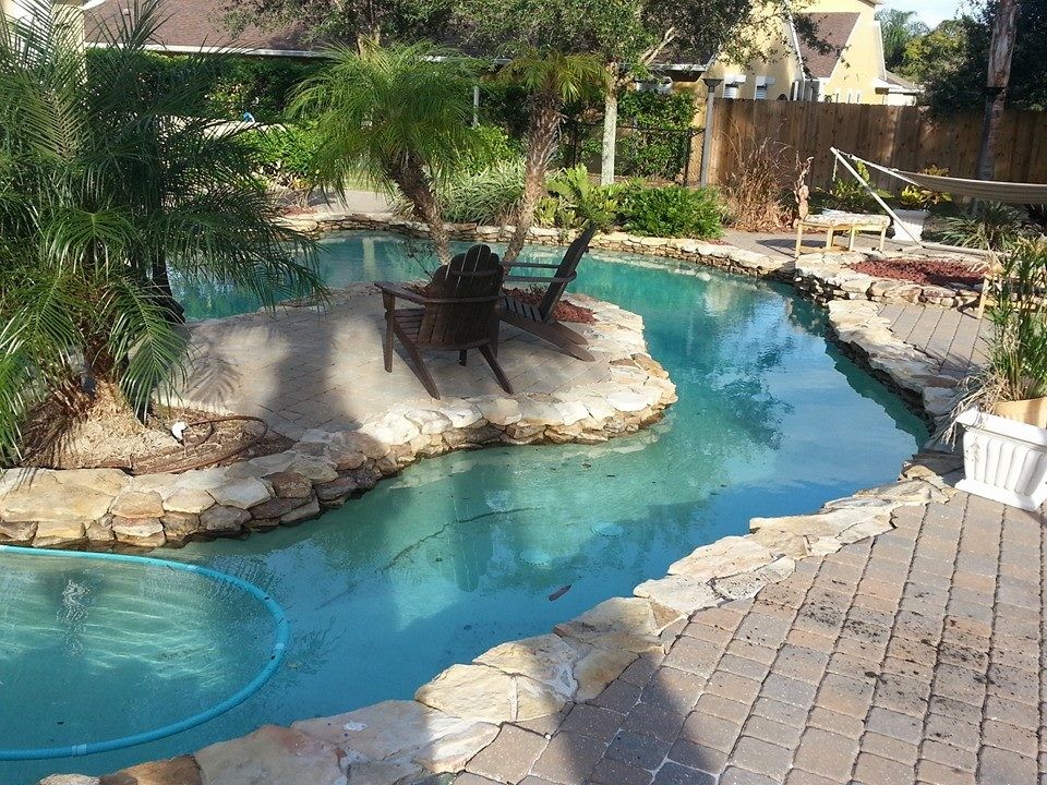 Ejemplo de piscina con fuente natural grande redondeada en patio trasero con adoquines de piedra natural