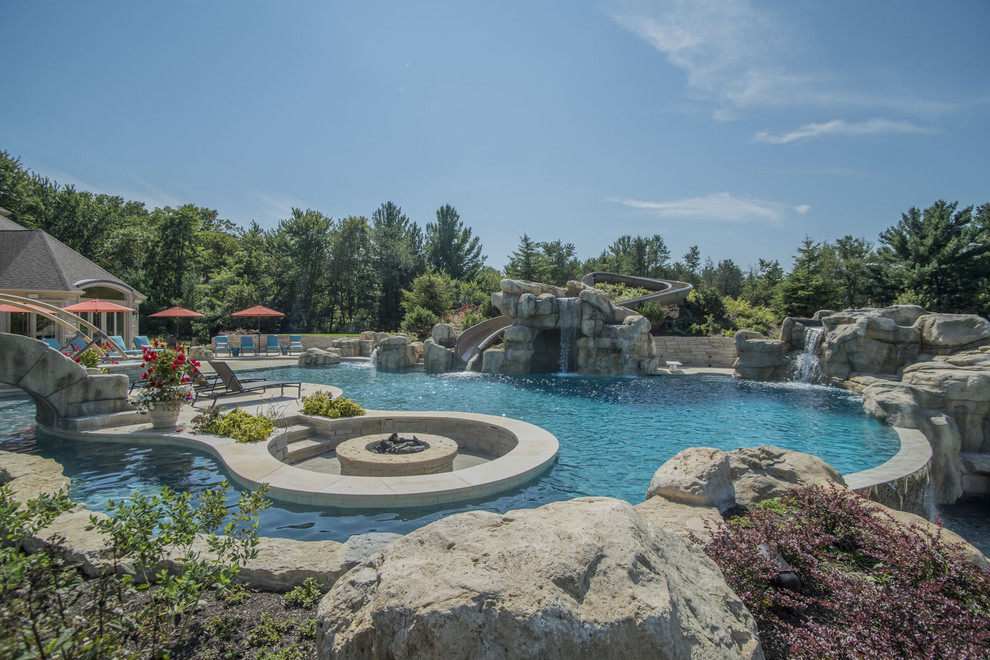 Cette image montre une très grande piscine arrière et à débordement sur mesure avec un point d'eau et des pavés en pierre naturelle.