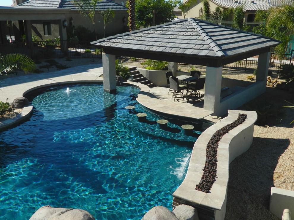 Imagen de piscina natural mediterránea grande a medida en patio trasero con adoquines de piedra natural
