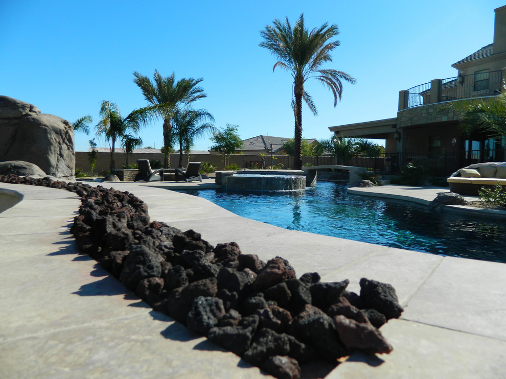 На фото: большой естественный бассейн произвольной формы на заднем дворе в средиземноморском стиле с покрытием из каменной брусчатки