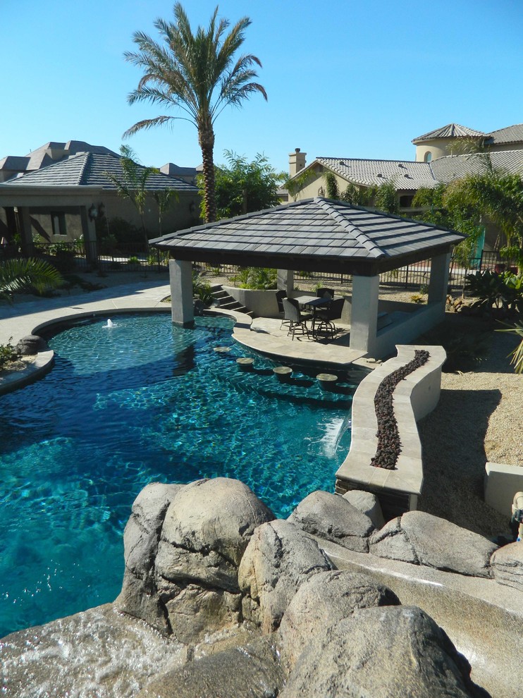 Design ideas for a large mediterranean back custom shaped natural swimming pool in Phoenix with natural stone paving.
