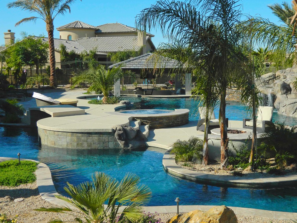Idee per una grande piscina naturale mediterranea personalizzata dietro casa con pavimentazioni in pietra naturale