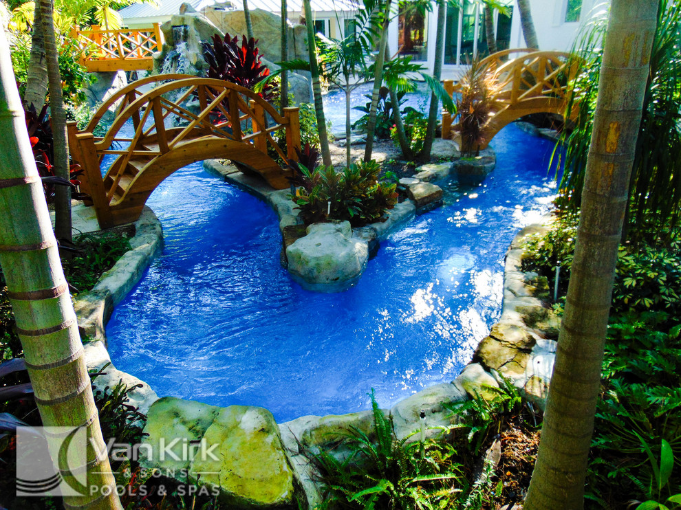 Geräumiger Schwimmteich hinter dem Haus in individueller Form mit Wasserspiel und Natursteinplatten in Miami
