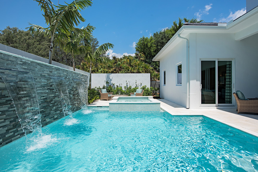 Mittelgroßer Moderner Pool hinter dem Haus in rechteckiger Form mit Wasserspiel und Natursteinplatten in Miami