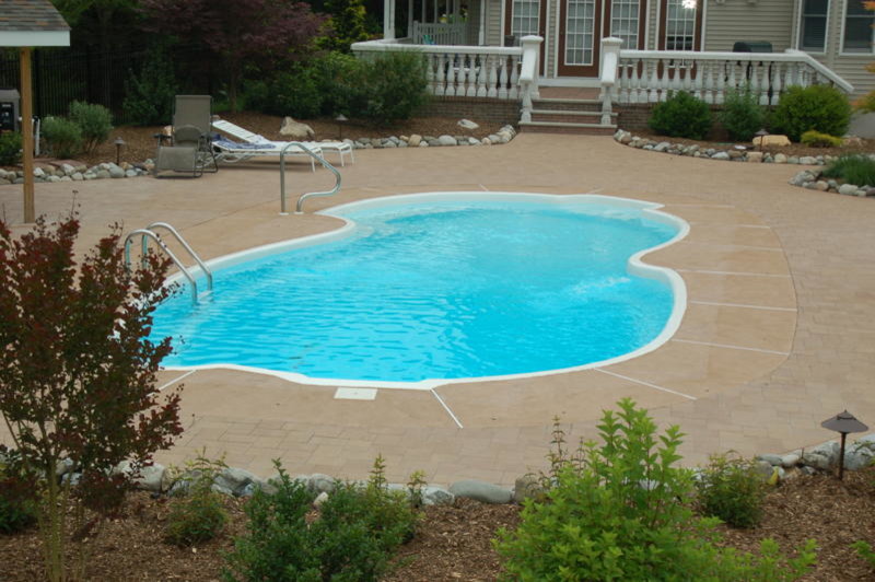 Foto på en mycket stor tropisk pool på baksidan av huset, med naturstensplattor