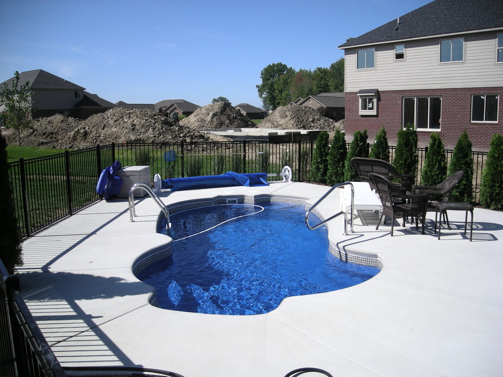 Modelo de piscina tropical extra grande a medida en patio trasero con losas de hormigón