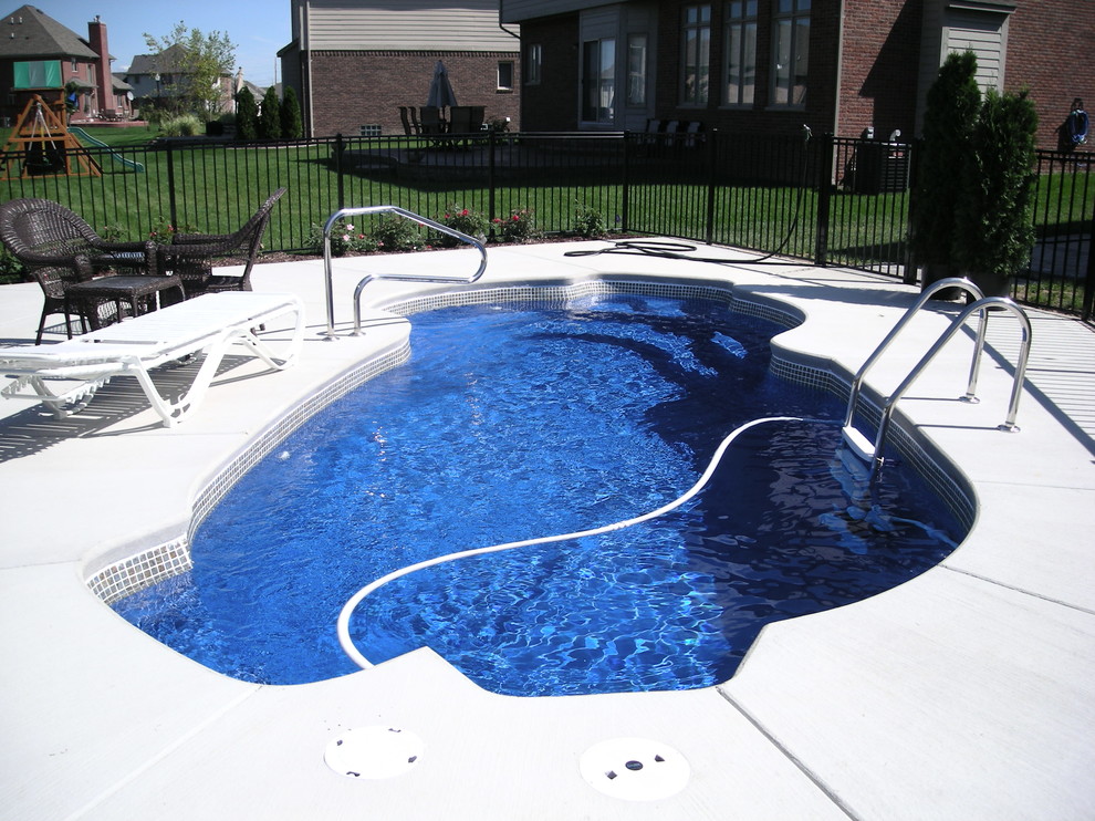 Immagine di un'ampia piscina tropicale personalizzata dietro casa con lastre di cemento
