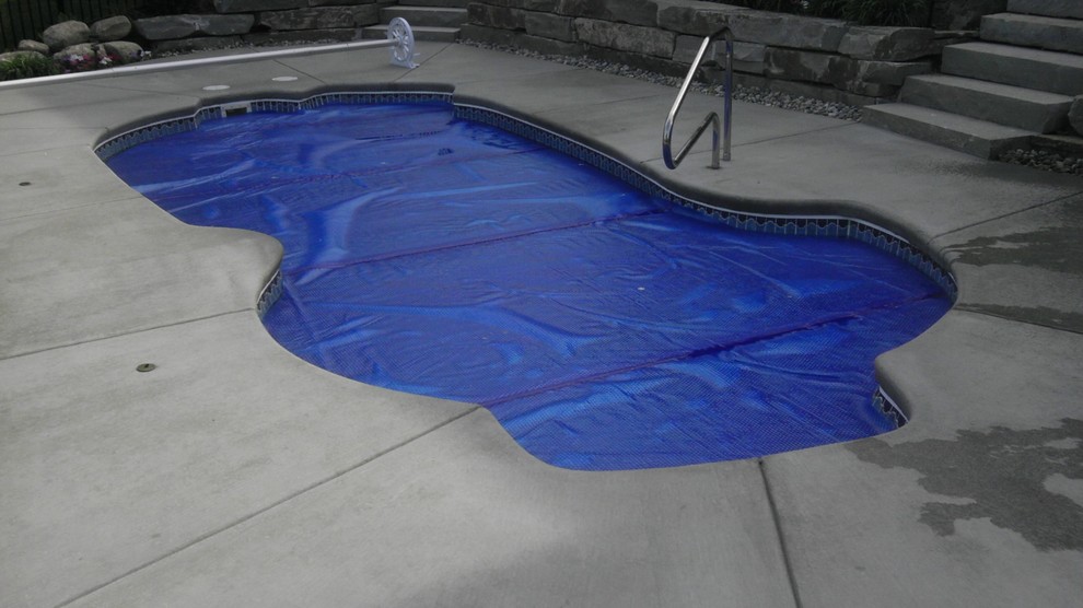 This is an example of an expansive world-inspired back custom shaped swimming pool in Other with concrete slabs.