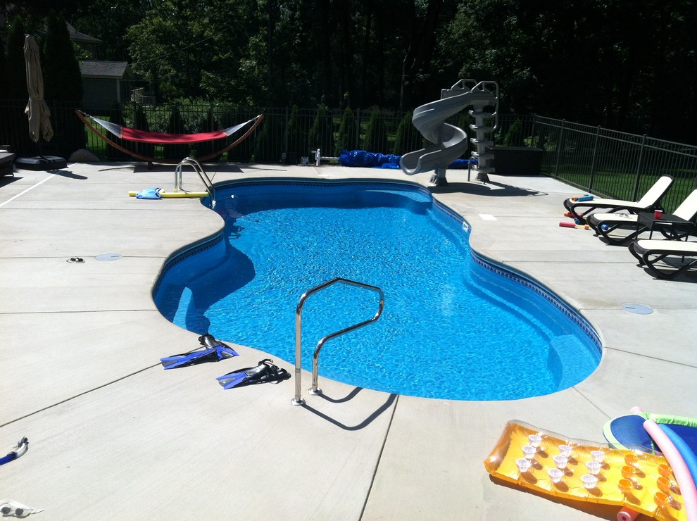 Réalisation d'une très grande piscine arrière minimaliste sur mesure avec une dalle de béton.