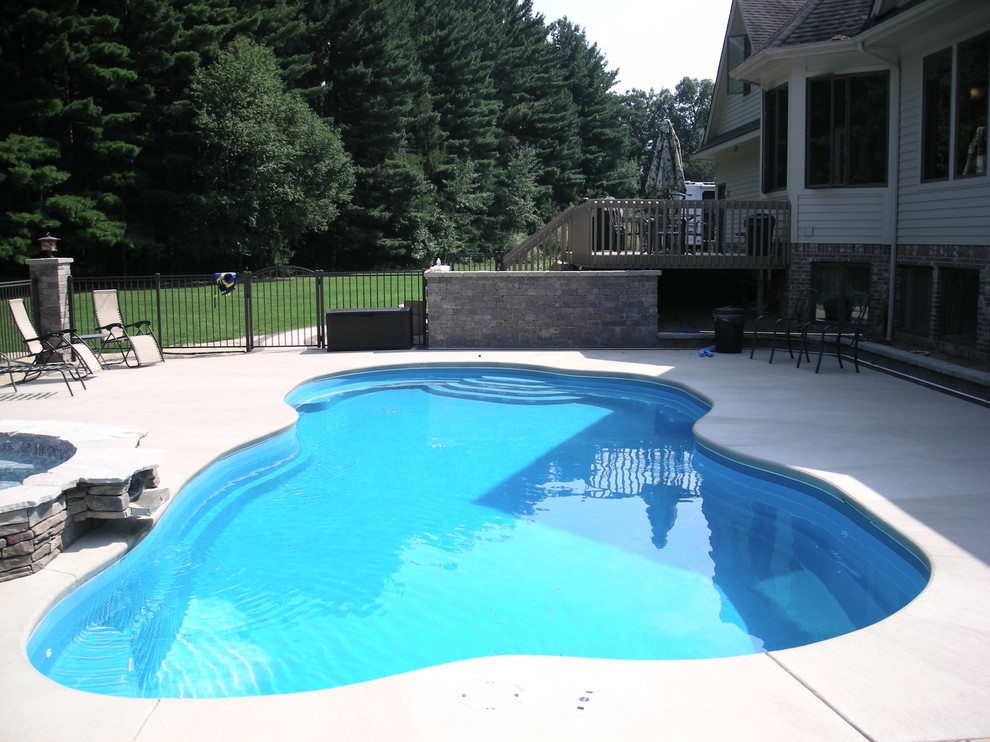 Inspiration för en mycket stor funkis anpassad pool på baksidan av huset, med betongplatta