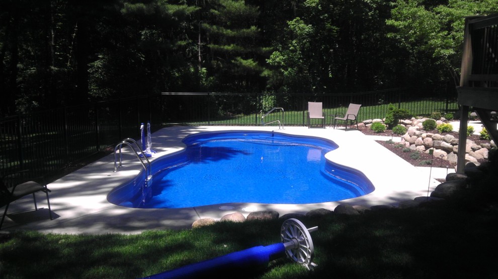 Foto di un'ampia piscina moderna personalizzata dietro casa con lastre di cemento