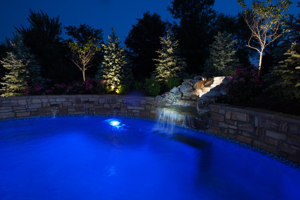 На фото: большой бассейн произвольной формы на заднем дворе в стиле неоклассика (современная классика) с фонтаном и покрытием из каменной брусчатки с