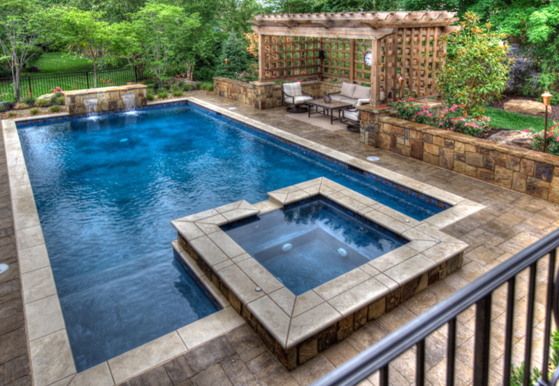 Modelo de piscinas y jacuzzis tradicionales de tamaño medio rectangulares en patio trasero con entablado