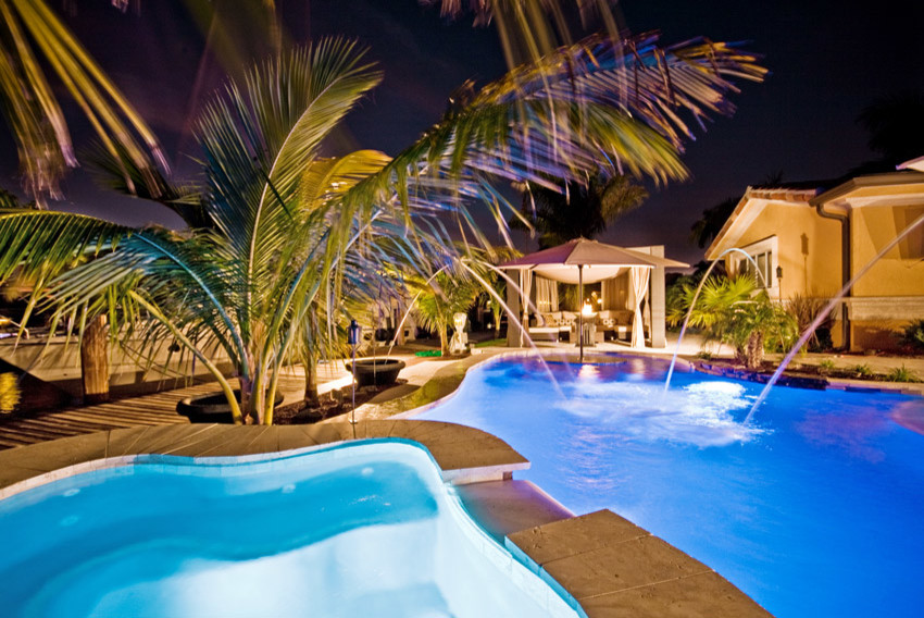 Mid-sized backyard stone and custom-shaped hot tub photo in Miami