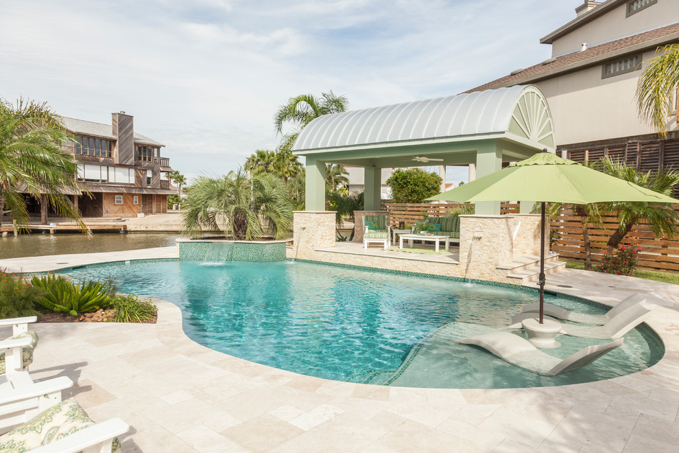 Ejemplo de piscinas y jacuzzis alargados tropicales de tamaño medio a medida en patio trasero con suelo de baldosas