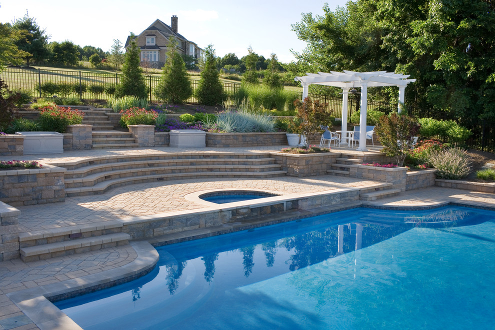 Modelo de piscina con fuente natural tradicional de tamaño medio a medida en patio lateral con adoquines de hormigón