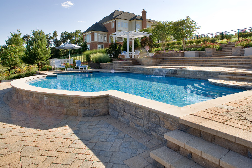 Diseño de piscina con fuente natural clásica de tamaño medio a medida en patio lateral con adoquines de hormigón