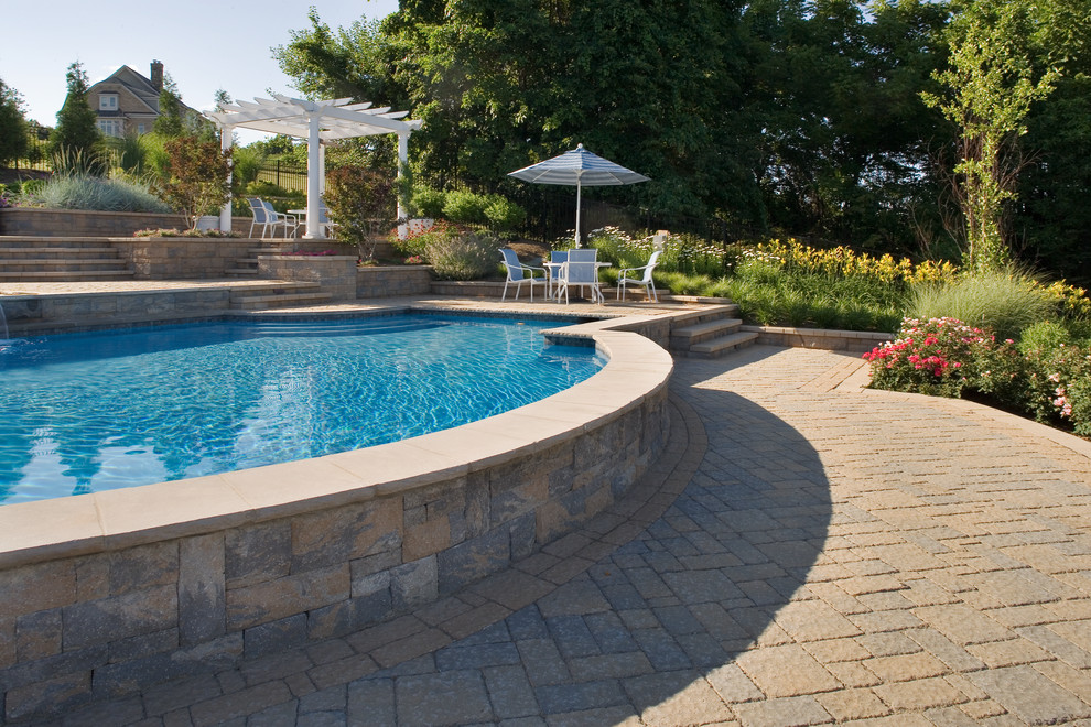 Ejemplo de piscina con fuente natural tradicional de tamaño medio a medida en patio lateral con adoquines de hormigón